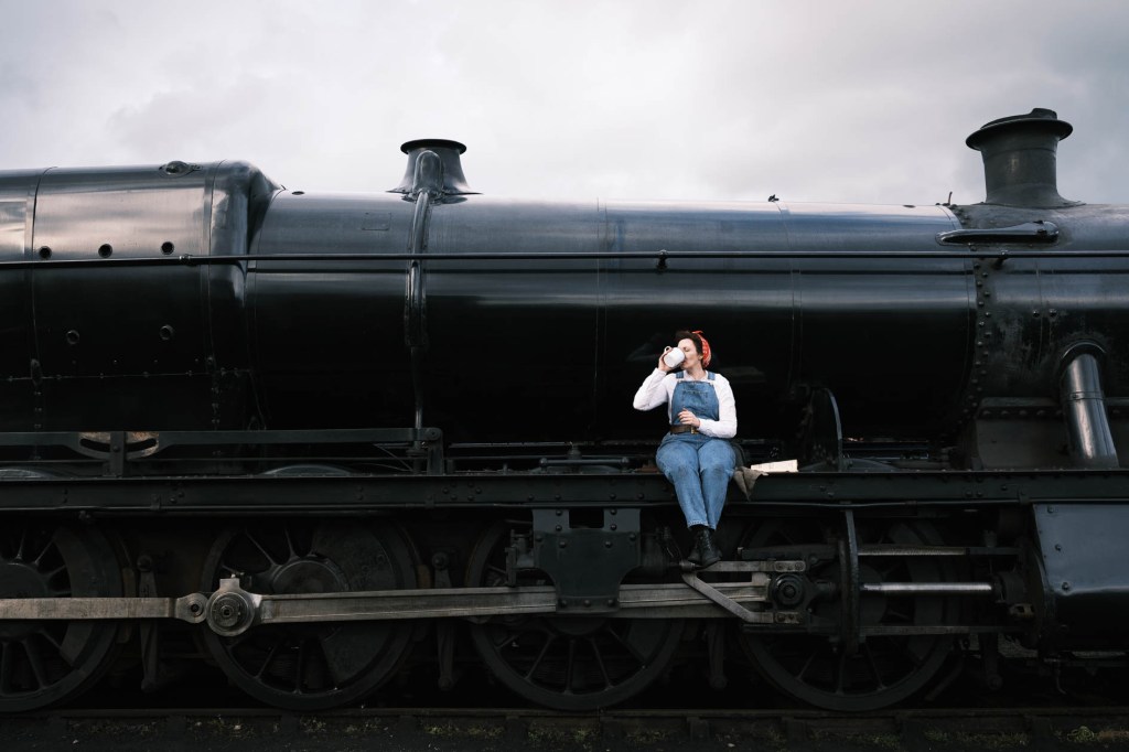 Woman drinking from a tea cup sitting on the side of a steam train. Nik Collection 6 Silver Efex test. 