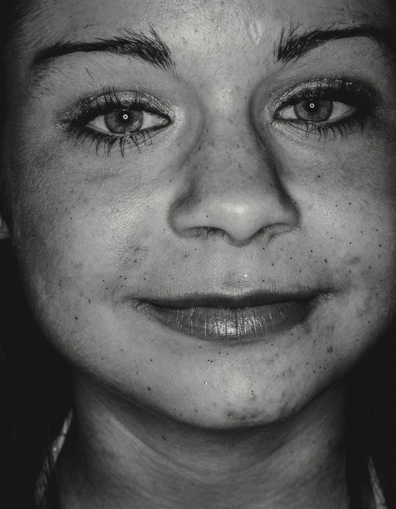 Close up black and white analogue portrait shot of a girl smiling at the camera