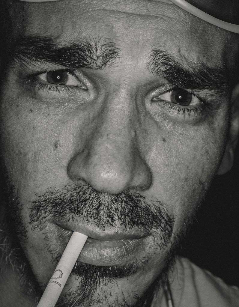 close up analogue street photo of a man with a cigarette in his mouth