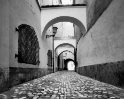 Narrow cobbled street with arches in black and white