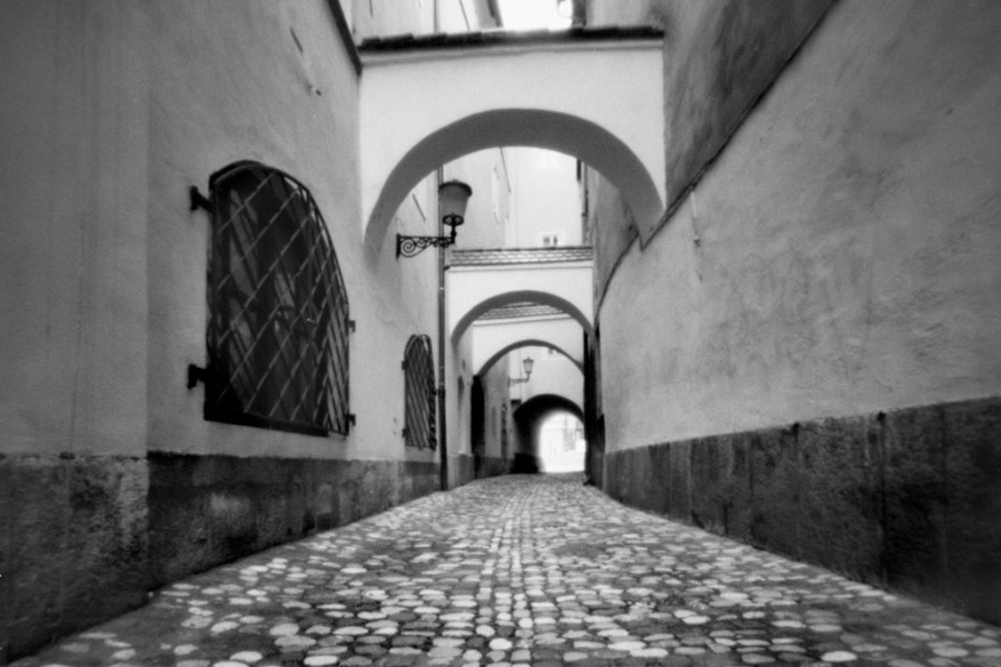 Narrow cobbled street with arches in black and white