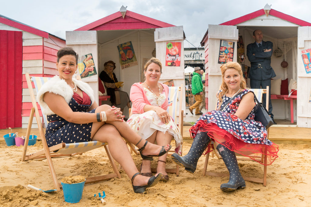 Three ladies dressed in retro sitting in front of beach cabins. Photoshop AI colouring example