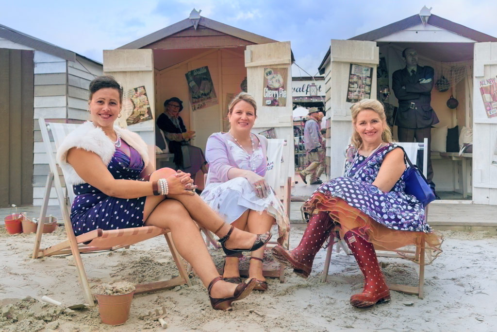 Three ladies dressed in retro sitting in front of beach cabins. Photoshop AI colouring example