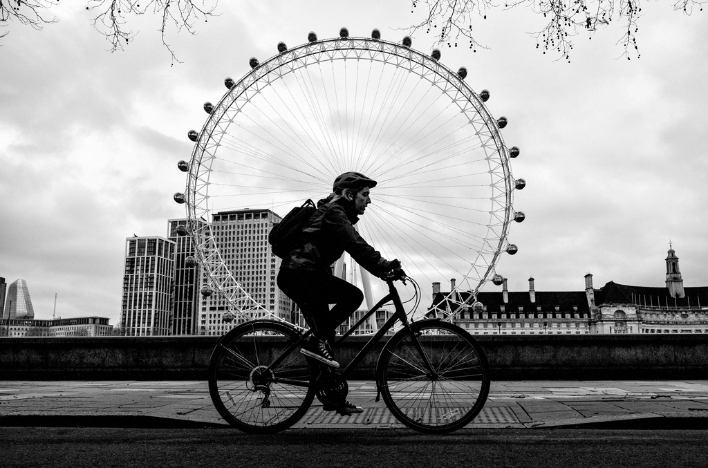 cyclist riding past the london eye north bank of the Thames