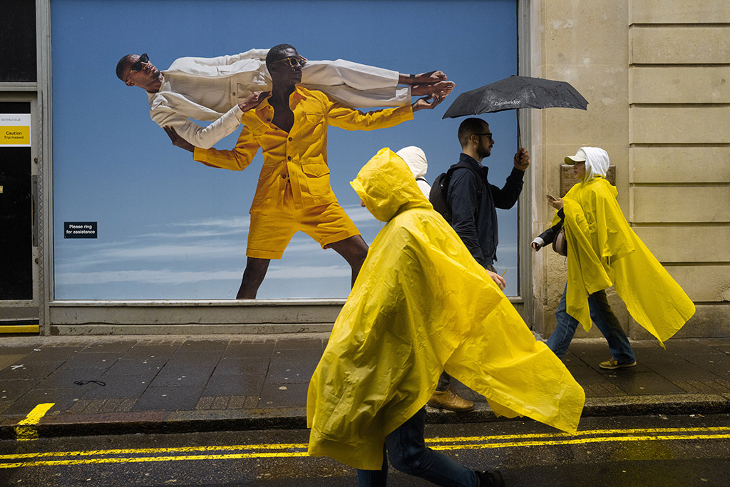 rainy street scene with people in yellow rain ponchos