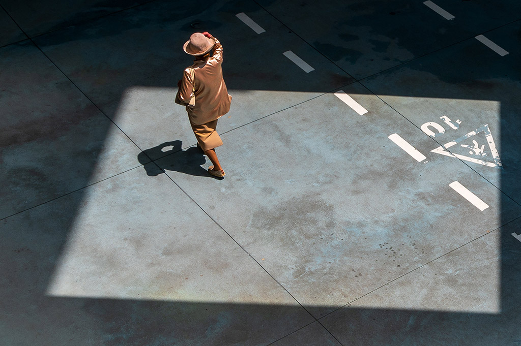 woman walking in bronze metallic outfit in square patch of light from sun apoy street top 10 