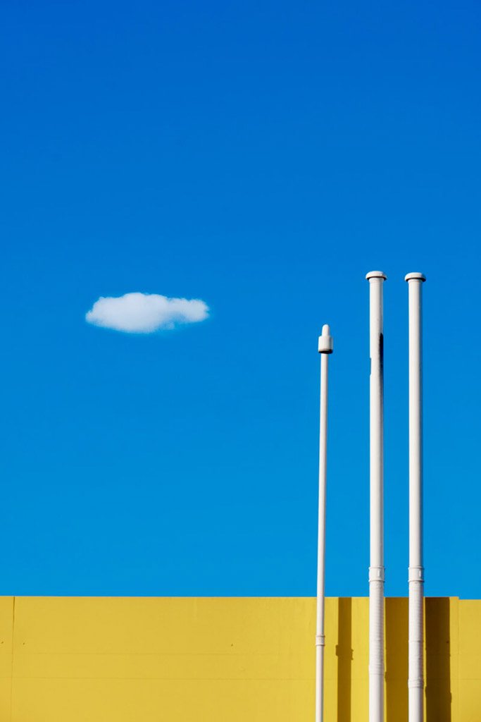 bright blue sky with single cloud contrasted with yellow building minimalist photography awards fine art winner