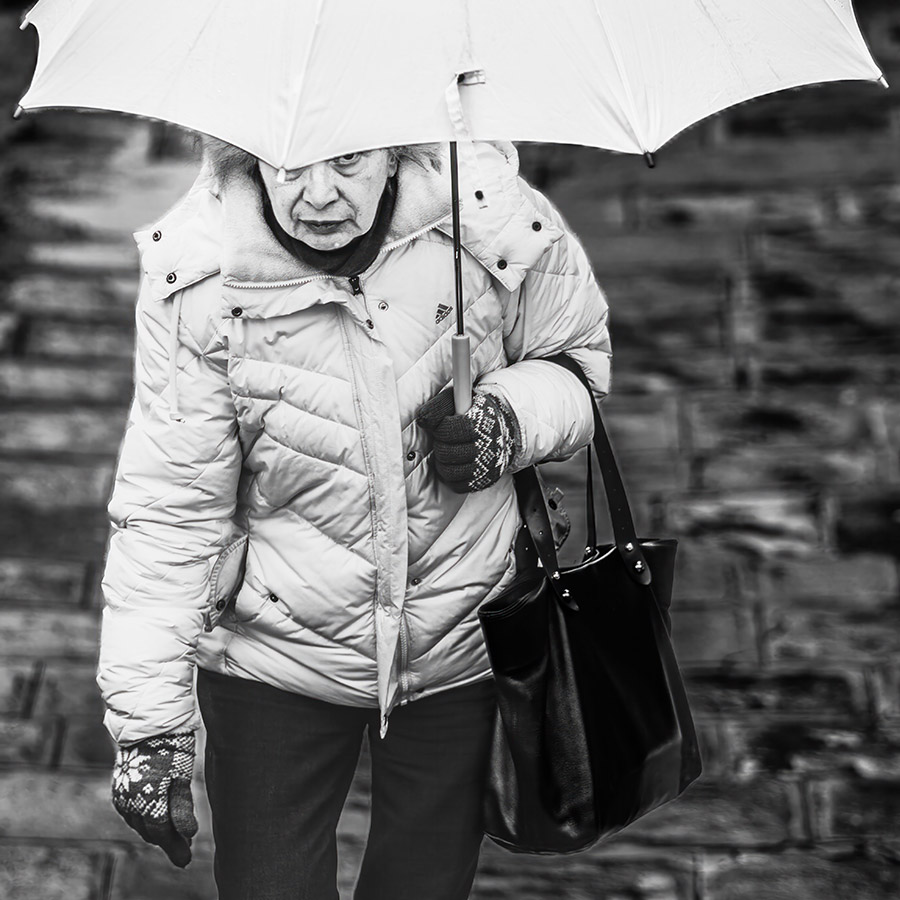 elderly woman looking out from beneath her umbrella