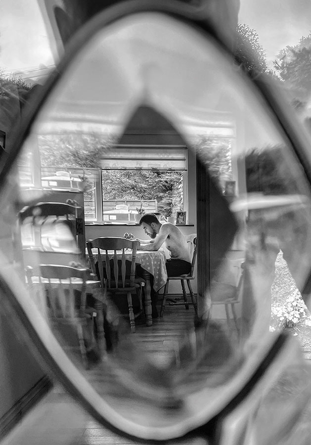 person sat at a kitchen table looking through glass iphone 12