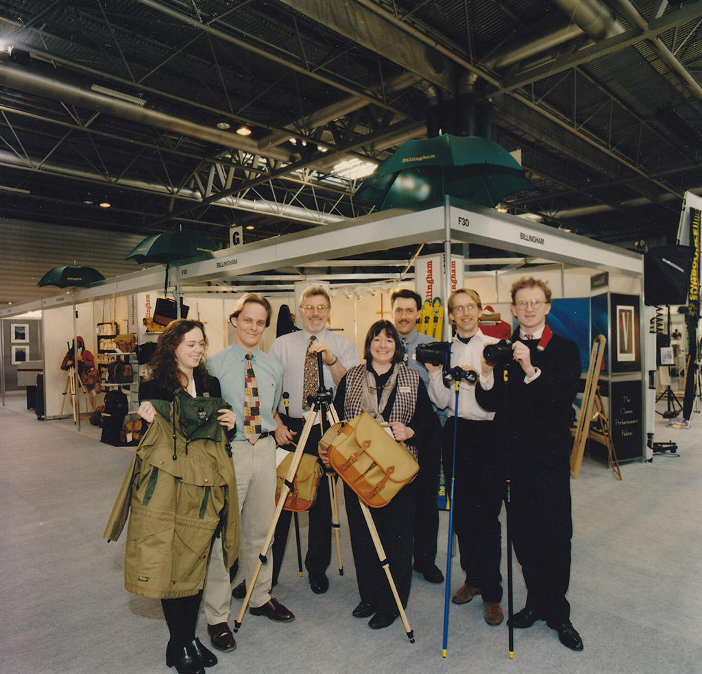 The Billingham stand at a photography show at the NEC, 1981. The photo features staff from Billingham and ‘CamCane’ which Billingham used to distribute. Ros Billingham is in the centre of the photo holding a Photo Eventer bag. © Tariq Chaudry