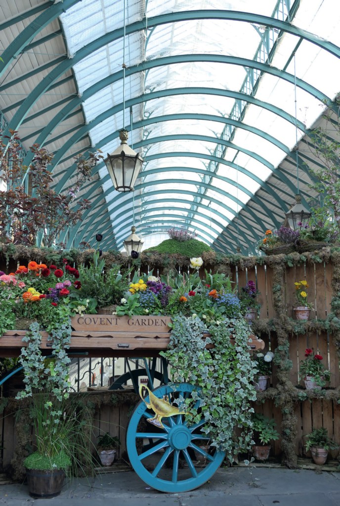 Panasonic Lumic FZ 1000 II Sample image. A large arched market pavilion's roof, in the foreground flowers hanging from a railing.