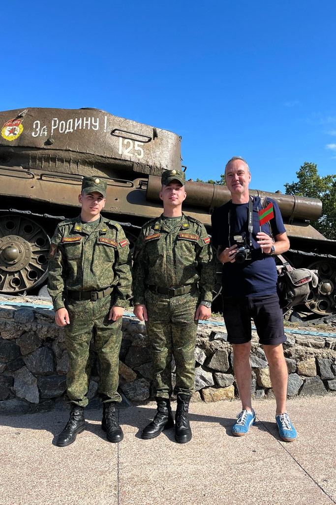 Dench next to a decommissioned T-34 tank with two members of the PMR military