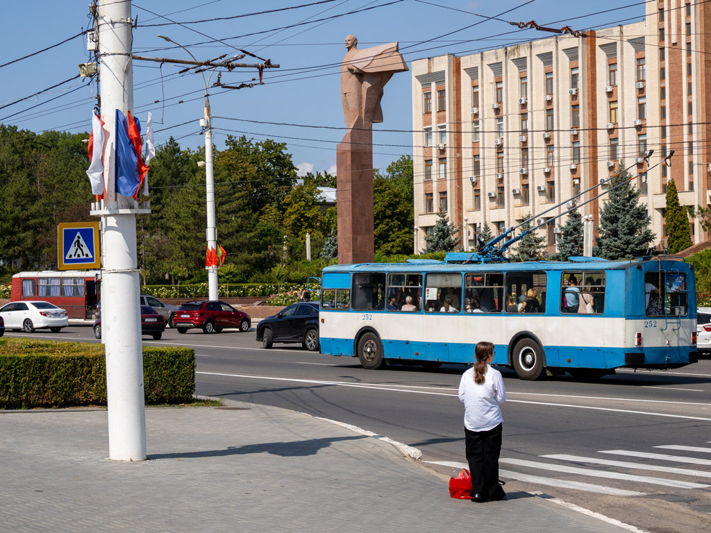 A statue of Lenin outside the monumental palace of the Supreme Council (Parliament) and the Government of Pridnestrovie, an old bus from the 80s passing in front
