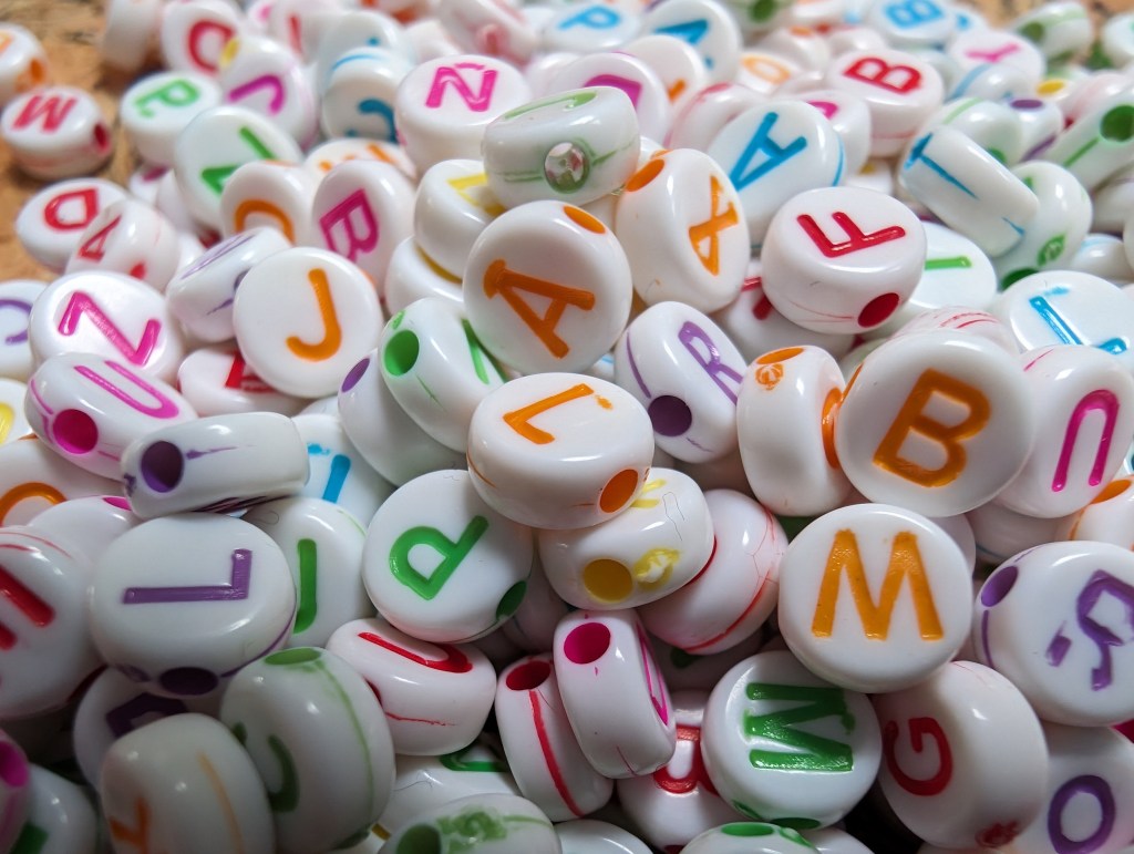 Google pixel 8 Pro macro sample image, white beads with colourful letters on them