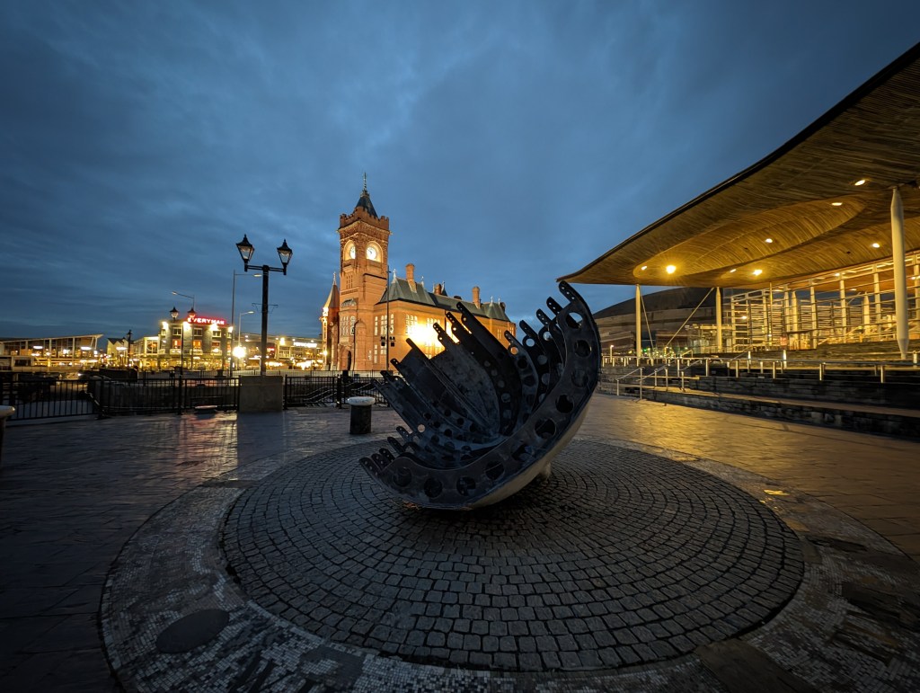 Google Pixel 8 Pro Night Sight Ultrawide lens sample image, modern sculpture at night in the background an illuminated clocktower