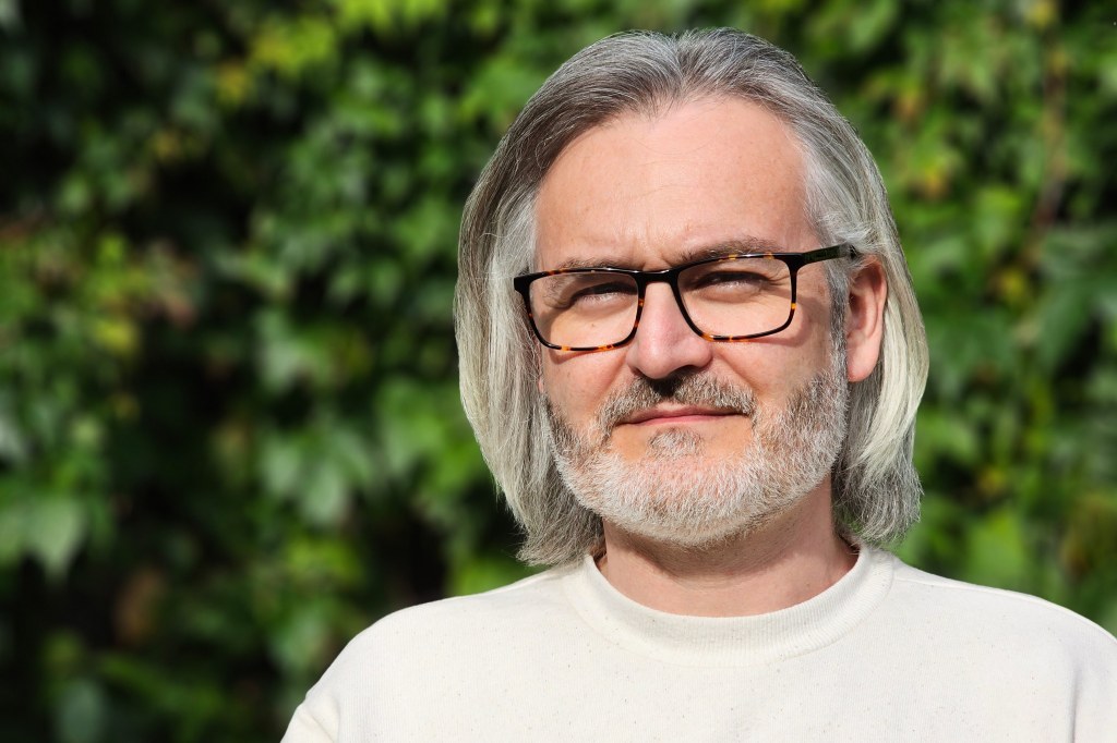 SamsungS23Ultra Portrait3x sample image. Portrait of a man with white shoulder length hair black glasses and short beard. credit: Amy Davies