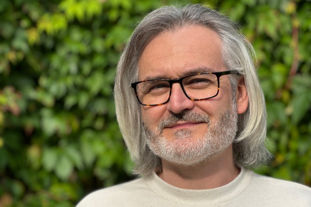 I Phone 15 Pro Portrait sample image 3x,Portrait of a man with white shoulder length hair black glasses and short beard. credit: Amy Davies