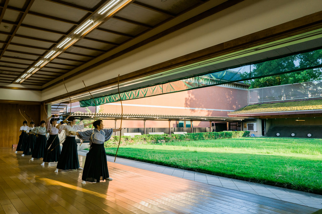 A group of people in traditional clothing practicing archery in a dedicated shooting range in Japan