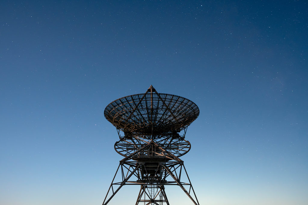 A radio telescope against a starry blue sky