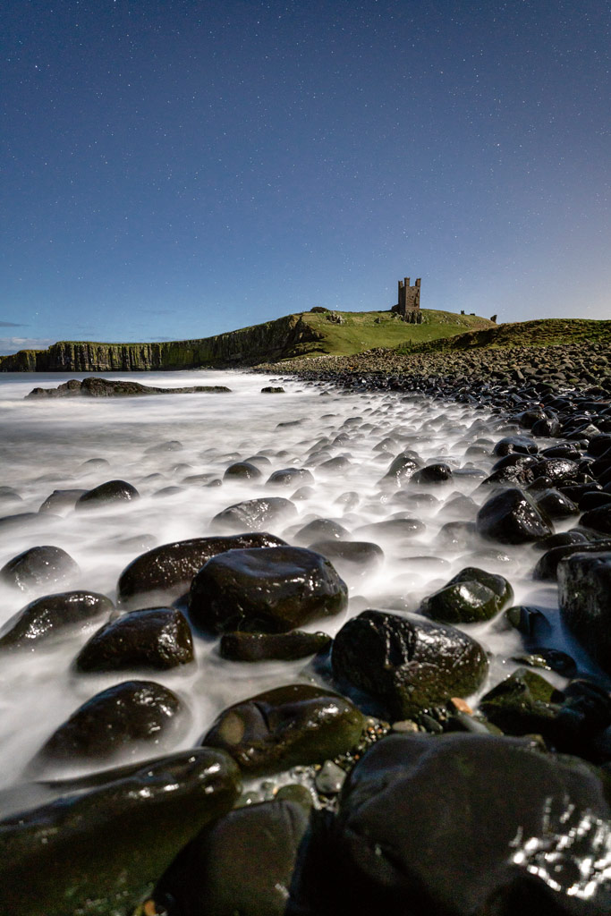 Dunstanburgh Castle in Northumberland shot from Embleton Bay under moonlight with stars visible in the sky. Image: James Abbott