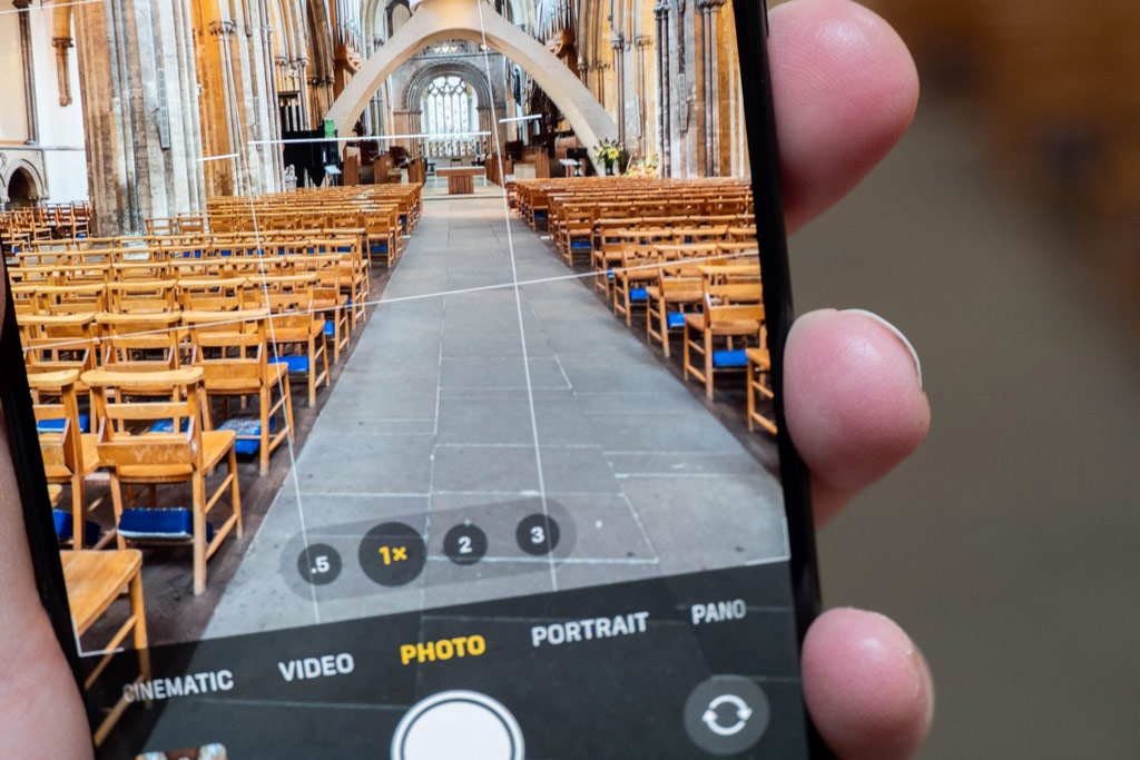 iPhone photography tips. iPhone grid feature activated, the phone displaying in live view a church interior with the isle and seats on each side