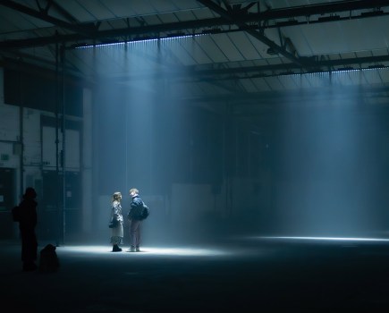 couple stood in spot light of low lit industrial building