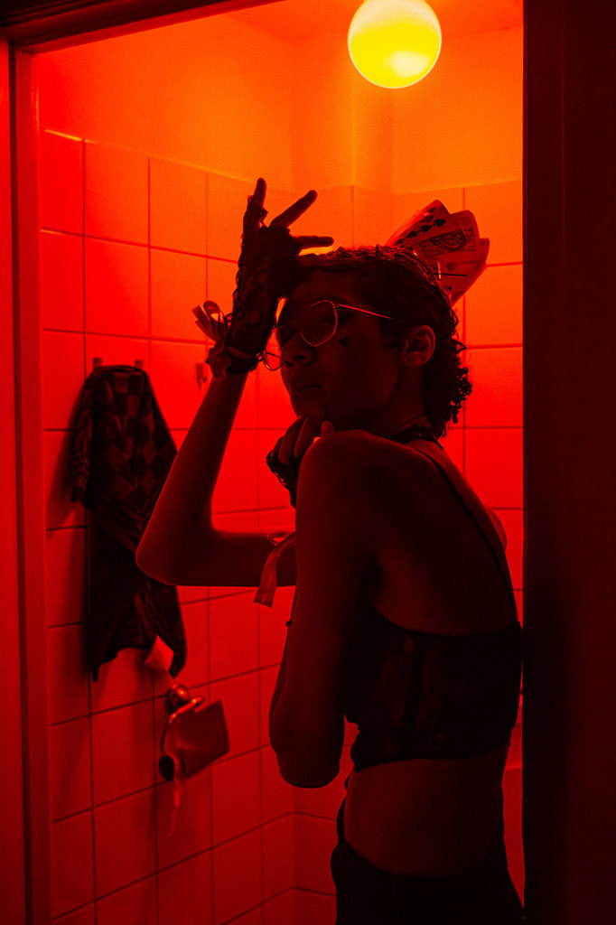 model posed in tiled room with bright red light