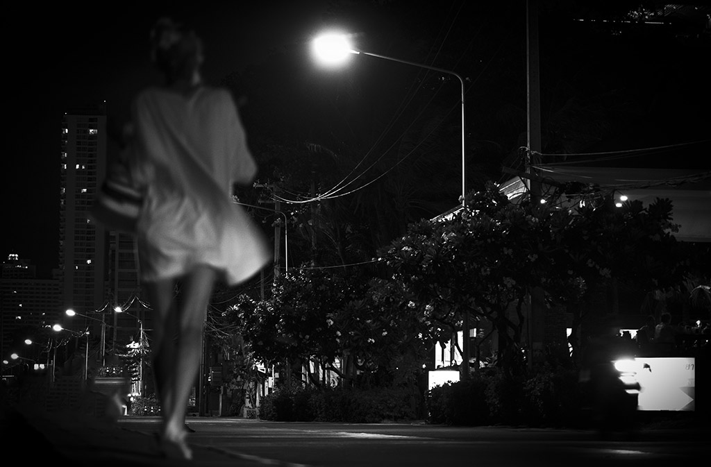 female figure out of focus running through street at night