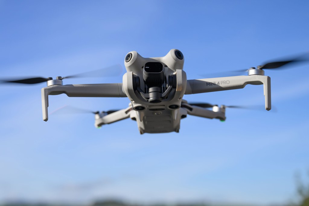DJI Mini 4 Pro Drone in flight against a blue sky