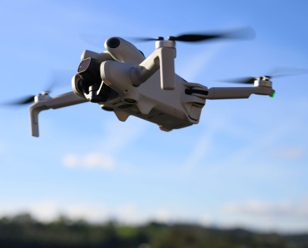 DJI Mini 4 Pro Drone in flight against a blue sky