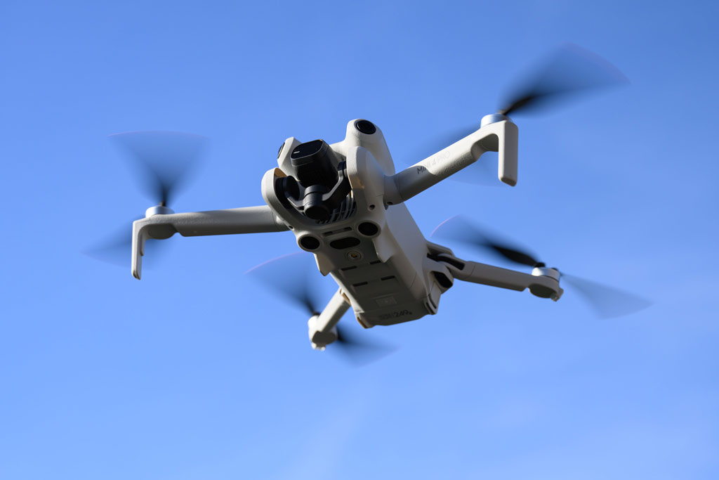 DJI Mini 4 Pro Drone in flight against a blue sky
