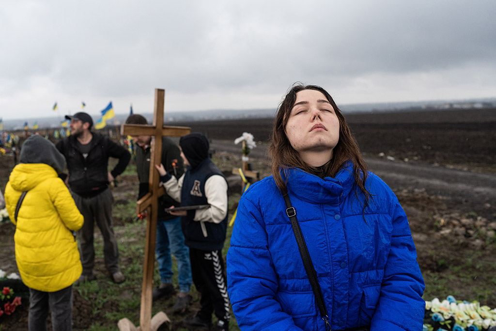 Yulia takes a moment to calm her emotions as her family installs a new wooden cross on her husband’s grave, Dnipro, Ukraine, 14 April 2023
