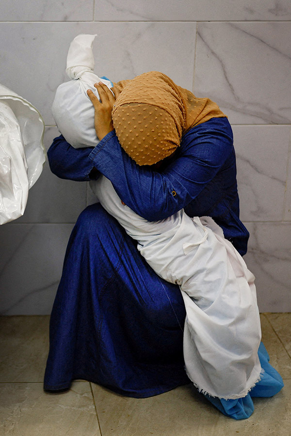 Palestinian woman Inas Abu Maamar, 36, embraces the body of her five-year-old niece Saly, who was killed in an Israeli strike, at Nasser hospital in Khan Younis in the southern Gaza Strip, 17 October 2023