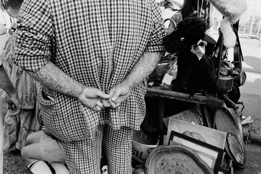 Joel Mayerowitz,black and white image of a man photographed from behind, with his hands behind his back, his arms covered in tattoo