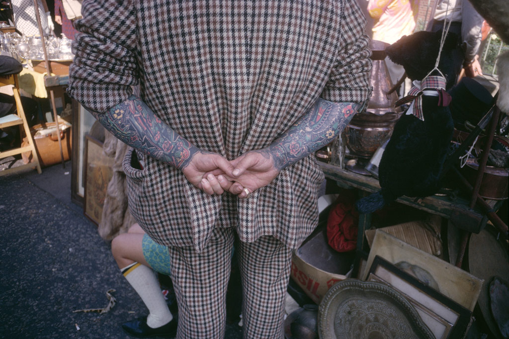 Joel Mayerowitz, a man photographed from behind, with his hands behind his back, his arms covered in colourful tattoo