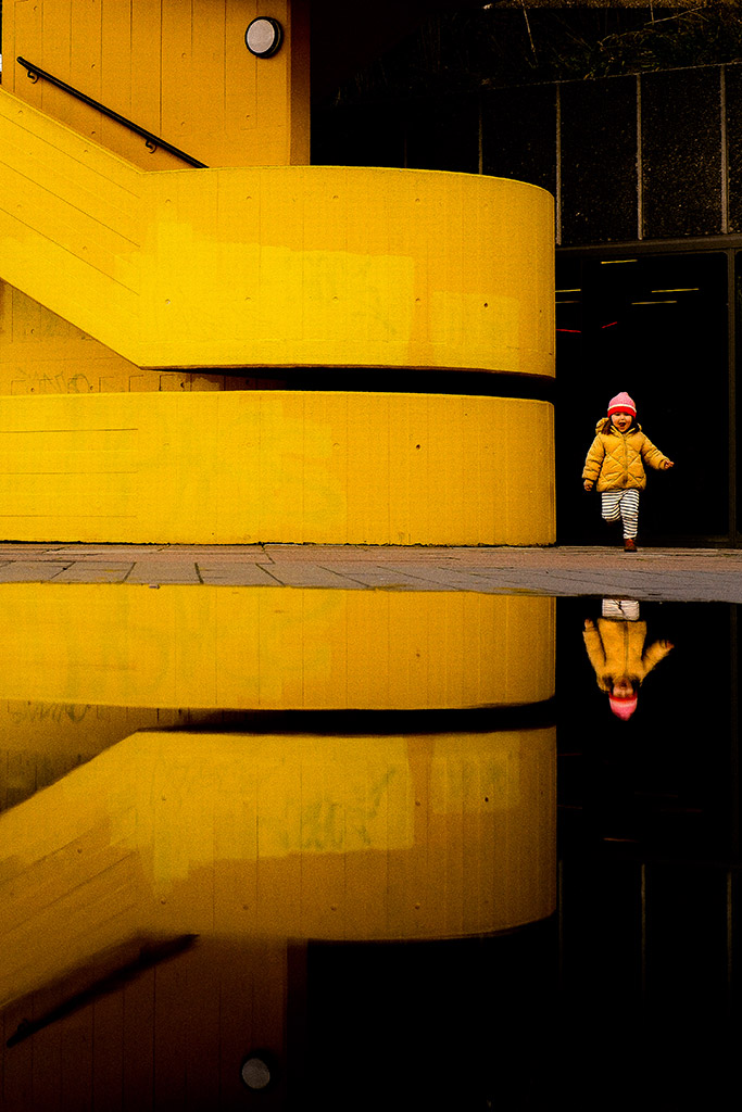 child in yellow coat runs around yellow southbank steps