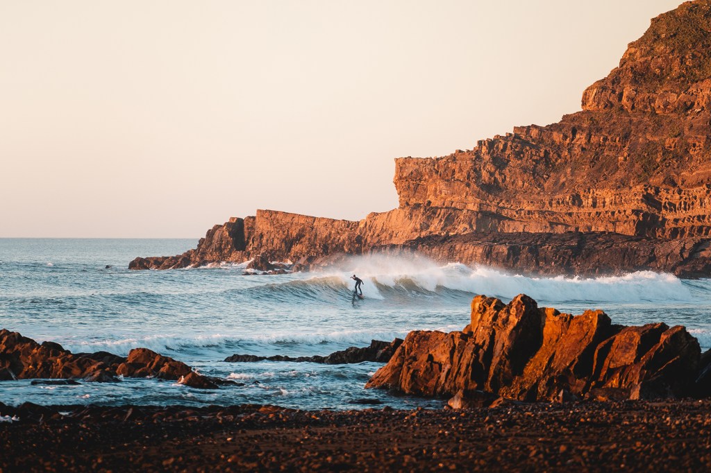 golden glow hitting the cliffs, and one lucky surfer all on his own