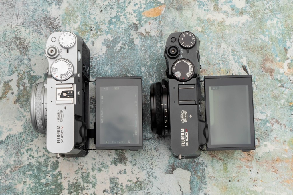 Fujifilm X100 VI vs X100 V cameras side by side top view with lcd screen tilted out