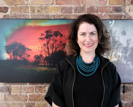 Portrait of Aletheia Casey at the World Press Photo 2024 exhibition in London posing in front of her work