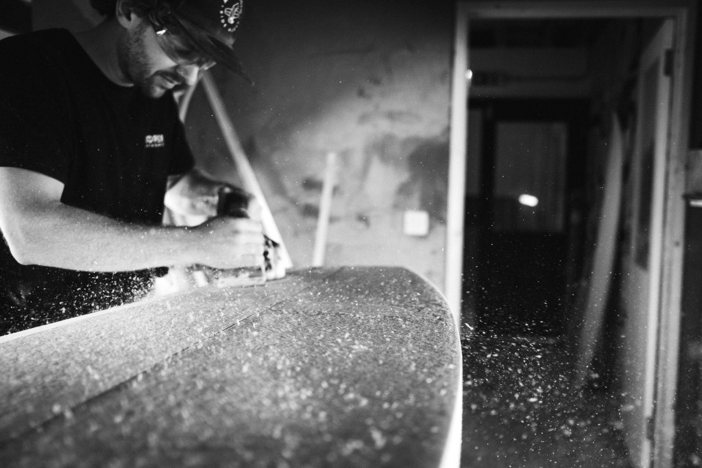 Fujifilm X100VI sample image in black and white, a man sanding a surfboard