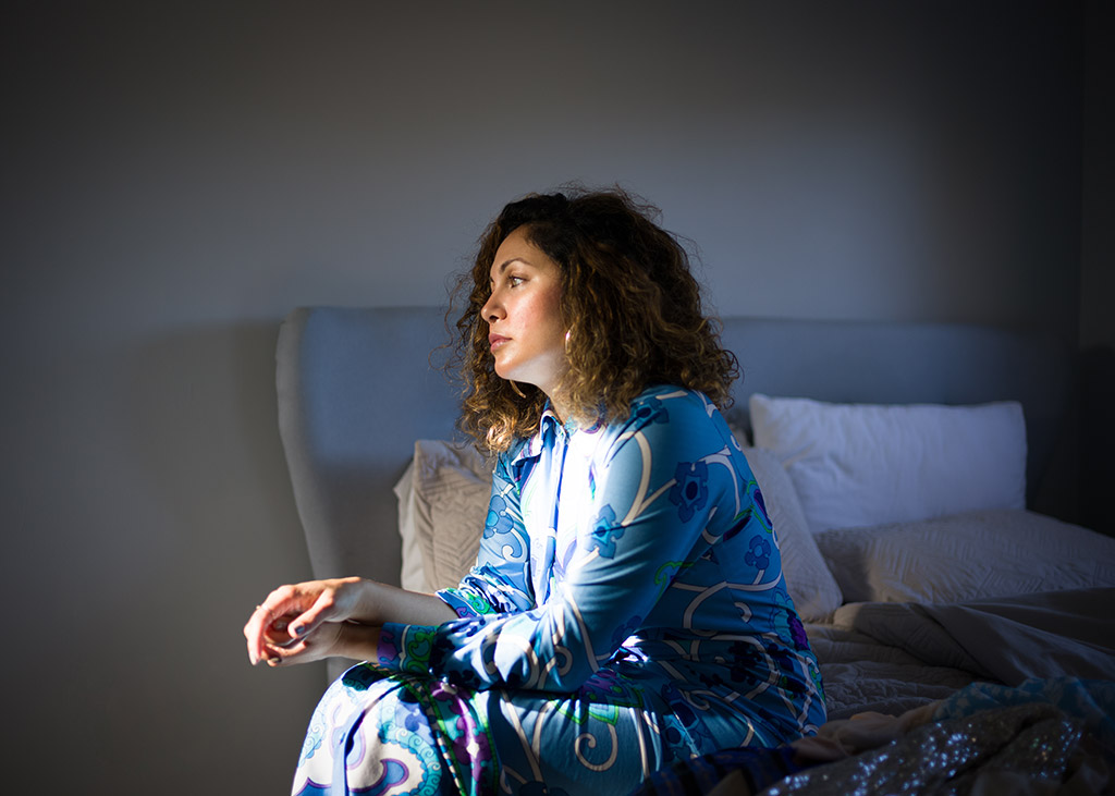 woman sat in bed room lit by the natural light through a window photo from photology exhibition