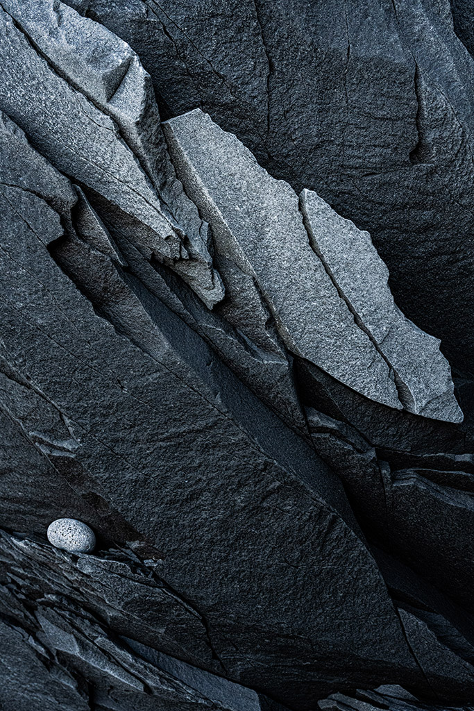 This natural abstract with its diagonal composition of fracture lines, fine grain textures, contrasting shades of grey, and focal point of a small, egg-shaped pebble tucked into a recess, is one of my favourites from the Vulcan series of images