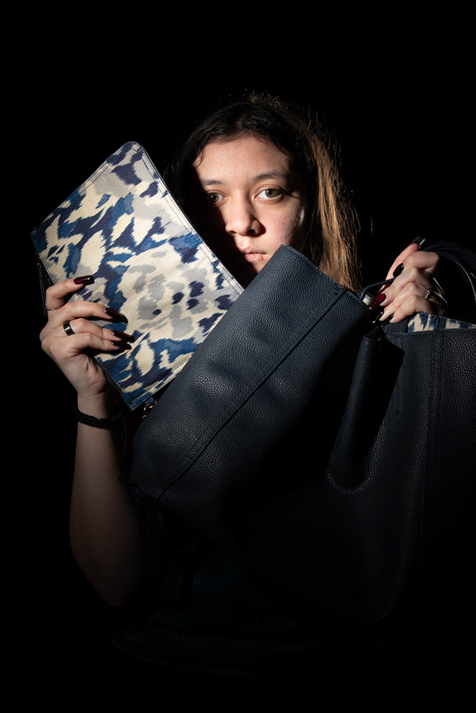 portrait of a woman holding up two blue bags photology exhibition