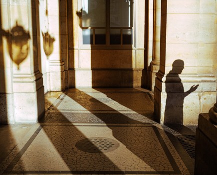 long shadows against building with person's silhouette to the right