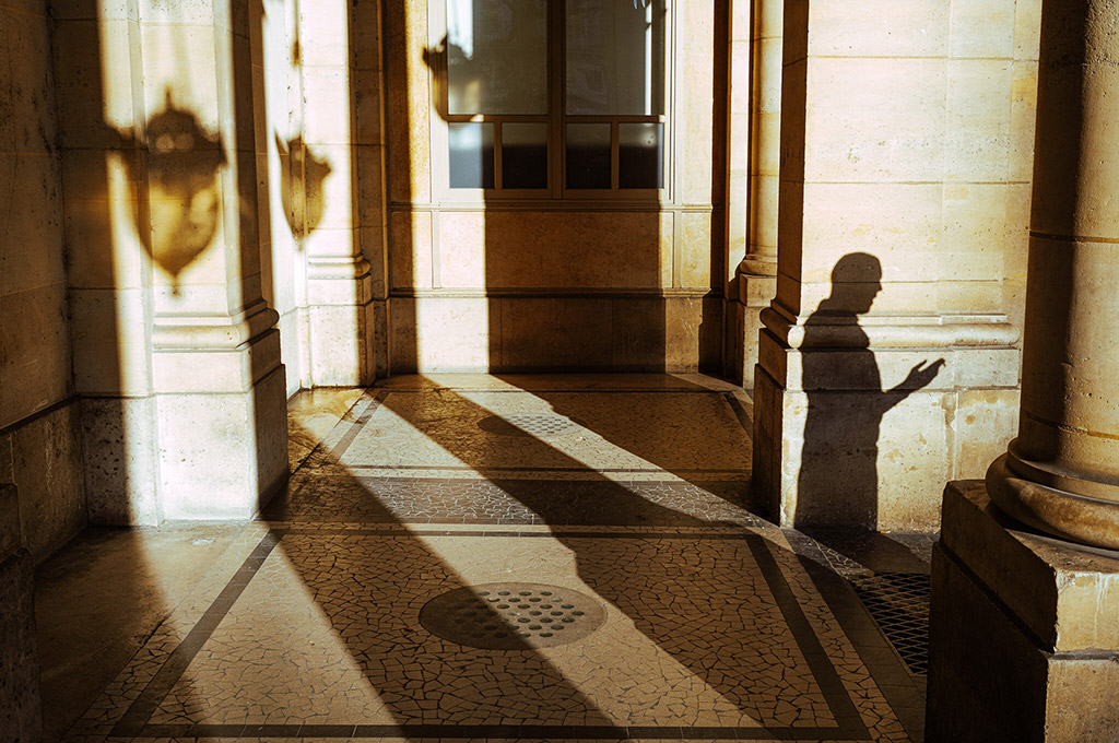 long shadows against building with person's silhouette to the right