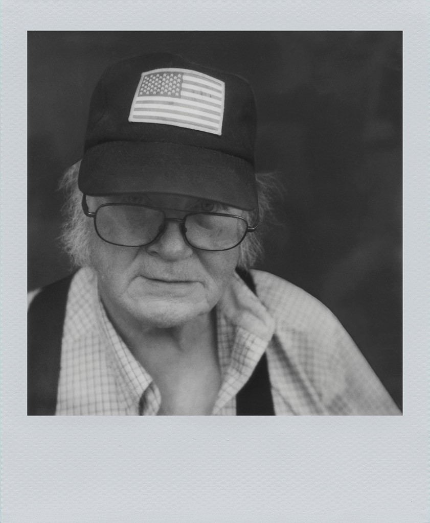 polaroid portrait of a older person weaing a baseball cap with the american flag