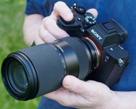 Hands holding Tamron 50-300mm f/4.5-6.3 lens mounted to full-frame Sony Alpha camera