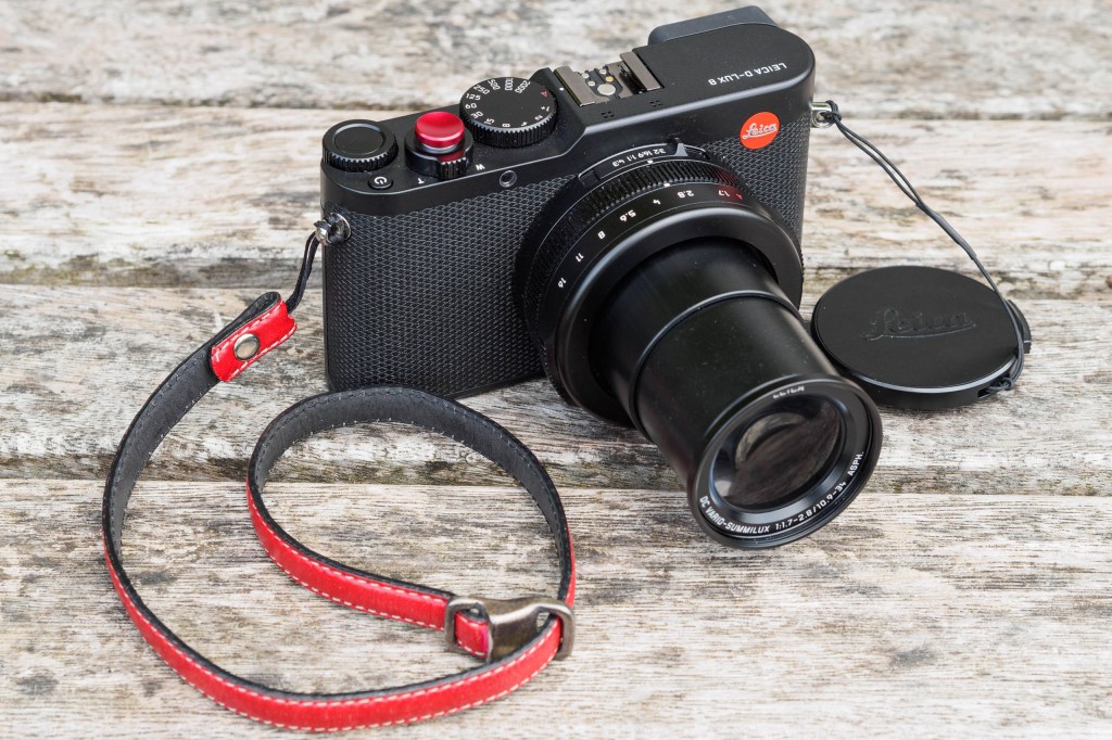 Leica D-Lux 8 with its clip-on lens cap plus third-party add-on shutter button and wrist strap