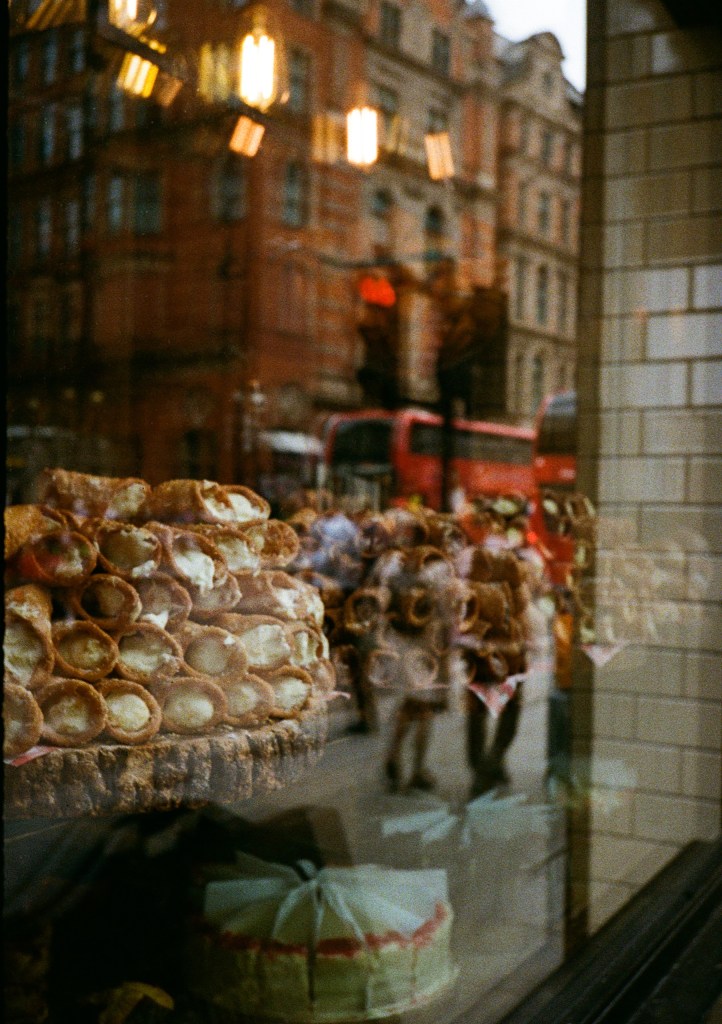 close up of shop window showing cannoli's with reflection of street