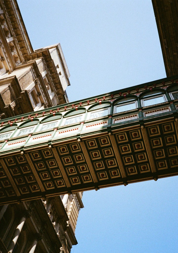 looking up at decorative bridge between 2 buildings